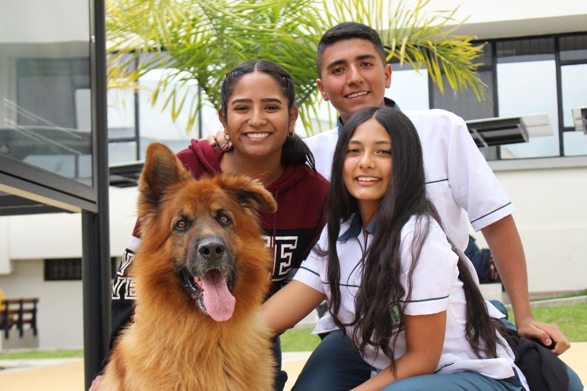 Jóvenes universitarios sonriendo, posando en foto con Nicky, la mascota de la UCM